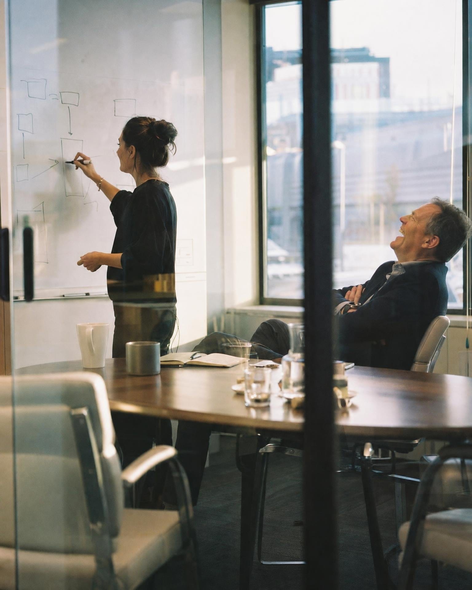 Ein Chief of Staff skizziert einen Plan auf einem Whiteboard, während der CEO lacht