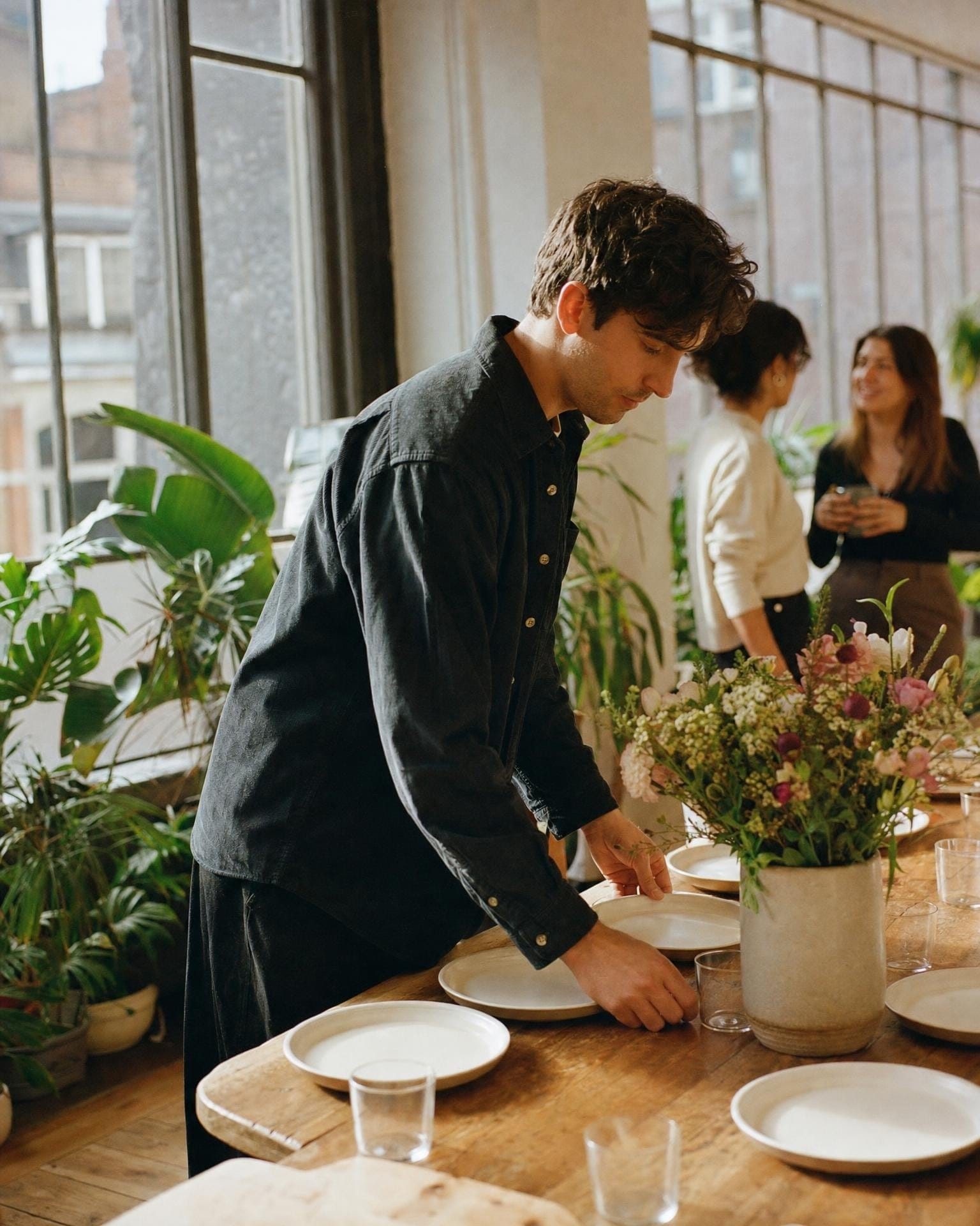 Eine Office Managerin deckt vor einem Team-Lunch den Tisch mit Blumen