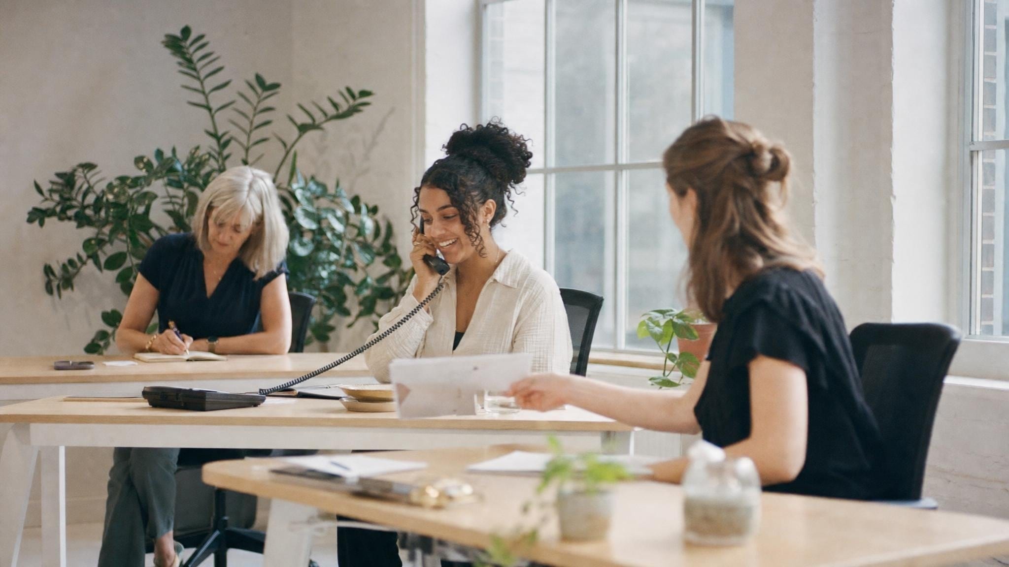Mitglieder des Dream-Teams bei der Arbeit in einem hellen Büro, eine Person telefoniert